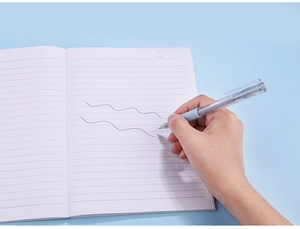 Detail view of transparent grey retractable gel pen writing on a lined white notebook