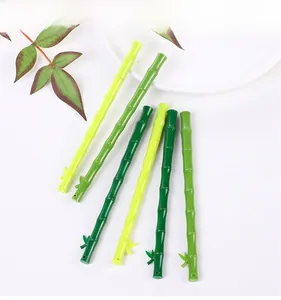 Bamboo shaped gel pens in gradient green tones with decorative leaves on white plate