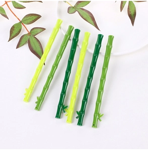 Detail of green bamboo-shaped gel pens with realistic leaf accents on white surface