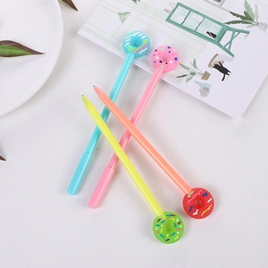 Stylos à gel créatifs en forme de donut en quatre couleurs sur un bureau blanc épuré