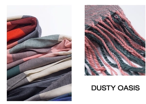 Detail of multi-color plaid knit scarf with thick twisted tassels and vibrant fiber textures