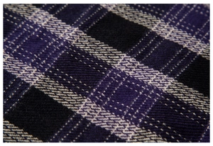 Dettaglio macro di sciarpa a quadri viola e neri con morbida trama a saia e fibre