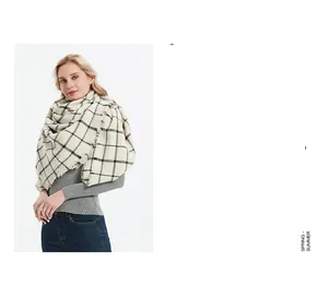 Detail of soft beige and black plaid scarf featuring fringed edges and thick texture