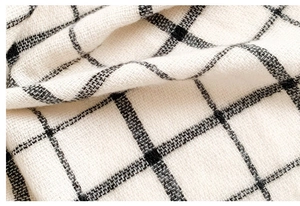Close-up of soft black and beige checkered fabric texture with visible wool-like fibers