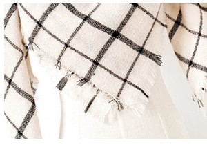 Detailed view of the soft black and cream checkered scarf with natural frayed edges