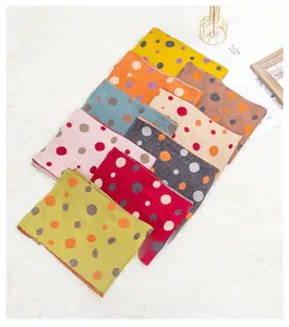 Close-up of colorful polka dot knit scarves in yellow, pink, and blue wool fabric
