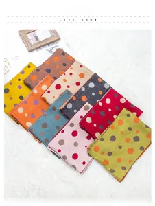 Detail of colorful polka dot knitted scarves with contrast stitching on plush rug