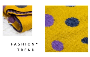 Detail of yellow knitted scarf with purple and gray polka dots showing texture
