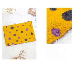Close-up detail of knitted yellow scarf with purple dots and soft warm wool texture