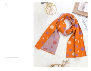Detail of reversible knit scarf featuring bright orange polka dots and purple stripes