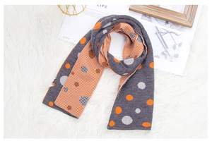 Detail of color-block knitted scarf with geometric dots and stripes on white fur background