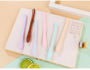 Penne gel creative a forma di scopa in colori pastello su un taccuino estetico