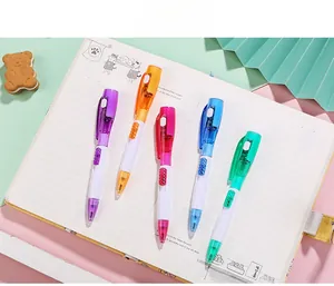 Cinq stylos à bille multifonctions avec lumière LED posés sur un carnet ouvert