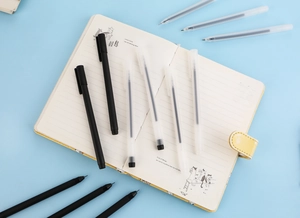 Detail of transparent frosted gel pens scattered on a yellow notebook in a minimalist desk setup