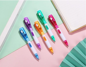 Cinq stylos à bille avec lampe LED colorée disposés sur un fond décoratif aux tons pastel