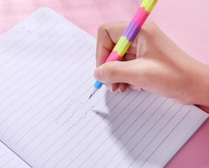Close-up of a hand writing on notebook with a multi-colored stackable building block pencil