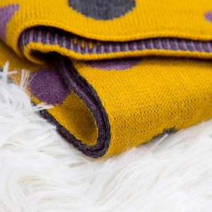 Winter kids knit scarf with yellow polka dots and warm ribbed edges on plush background