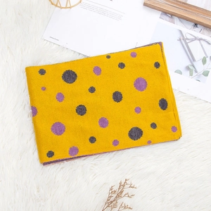 Cozy bright yellow knitted scarf with purple and grey polka dots on soft white rug