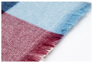 Close-up of high-density plaid scarf fabric showing blue and red weave with soft fringe