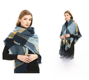 Détail d'une écharpe à carreaux bleus et moutarde en fil bouclé avec bordures à franges