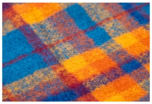 Macro shot of fluffy plaid winter scarf featuring bright blue and orange woven fibers