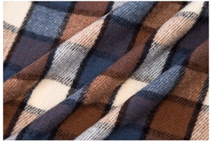 Detailed texture of thick plaid scarf in caramel brown, navy blue, and cream weave
