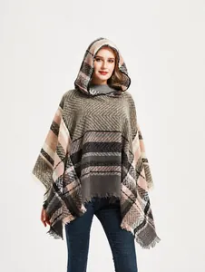 Detail van de gebreide poncho met capuchon, ruitpatroon, visgraatmotief en franje aan zoom