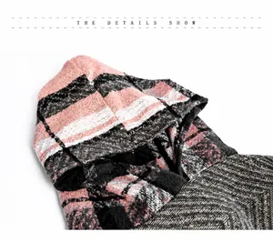Detailopname van de roze en zwarte geruite gebreide stof van een poncho met capuchon