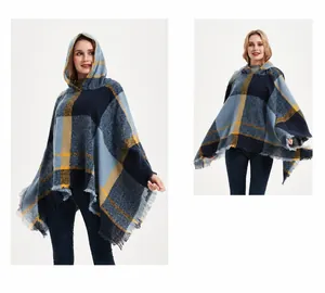 Detail eines karierten Kapuzenponchos mit marineblau-gelbem Muster und Fransen am Saum