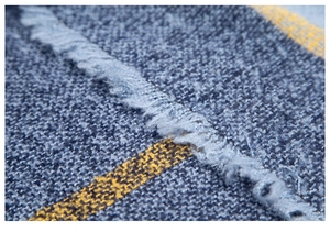 Makroaufnahme von dunkelblauem Poncho-Stoff mit gelben Streifen und weichen Fransendetails