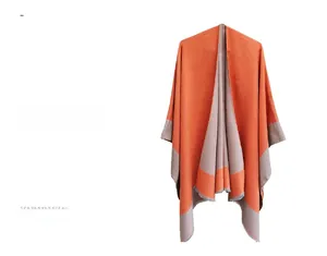 Detail of knit shawl featuring orange and taupe color-block design with fringe edges