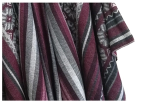 Detail of geometric jacquard patterns on red and grey ethnic shawl with tassel edges