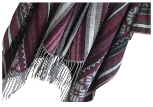 Detail of bohemian geometric jacquard knit shawl with long grey fringe hem and tassels