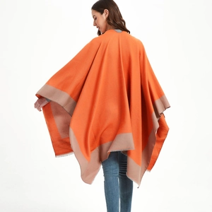 Orange and beige knit poncho shawl with fringe detail shown on a model from the back