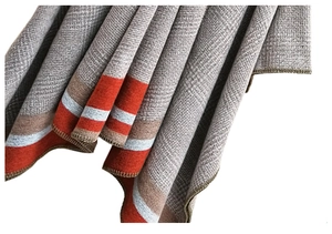 Detailed close-up of grey herringbone knit shawl with orange and blue stitched edges