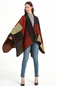 Dettaglio del poncho in maglia a motivi geometrici con blocchi di colore rosso, giallo e grigio