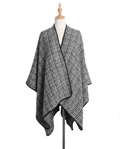 Détail de la texture pied-de-poule et de l'ourlet noir sur un châle cape pour femme