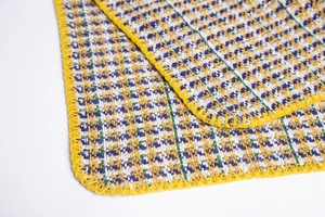 Détail du tissu pied-de-poule jaune avec fil métallique scintillant et bordure cousue