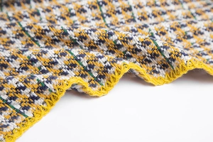 Gros plan sur un tissu en tweed pied-de-poule avec fils d'argent et coutures jaunes