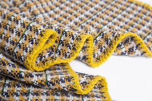 Gros plan sur un tissu en maille pied-de-poule jaune et bleu avec fils brillants et coutures