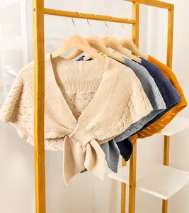 Détail de châles en tricot beige, gris, bleu et jaune avec textures ondulées ajourées