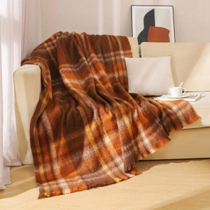 Close-up of brown and orange checkered knit throw blanket with decorative fringe detail