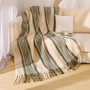 Detail of Nordic knit throw blanket featuring grey stripes and soft fringe on a sofa