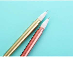 Detalle de bolígrafos de metal dorado y oro rosa con puntas finas sobre fondo azul