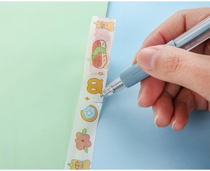 Detail eines grauen Stift-Cuttermessers beim Schneiden von Washi-Tape auf geteiltem Hintergrund