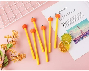 Close-up of cute pumpkin gel pens with orange decorative caps on a stylized desk