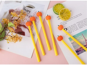 Detail shot of six creative pumpkin gel pens scattered on a pink desktop with props