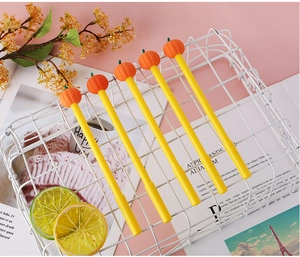 Close-up of five creative yellow gel pens with cute orange pumpkin toppers in a basket