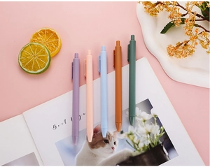 Detailed close-up of five colorful morandi gel pens on a pink aesthetic desk setup