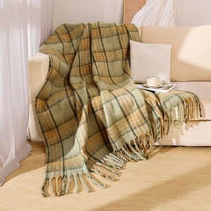 Detailed close-up of retro plaid throw blanket with tassels draped on a beige sofa